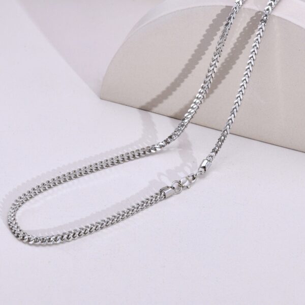 a silver chain on a white surface